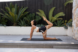 Woman practicing yoga outdoors on a wooden deck with the BAHE Flowloop band in action.