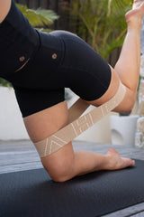 Person wearing a BAHE Flowloop on their ankle while sitting on a yoga mat outdoors.